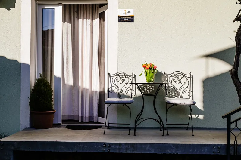 Eingang zum Studio über die Terrasse mit schmiedeeisernem Tischchen und Tulpen